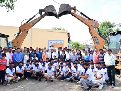 A group of individuals gathered in front of two large CASE excavators with their digging buckets crossed above, creating an arch. This ceremonial or celebratory moment highlights the completion of a project or a workforce gathering, symbolized by the excavators’ buckets.
