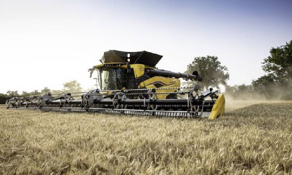 A large yellow New Holland combine harvester working in a field of golden wheat, efficiently reaping and collecting the crop. This image highlights modern agricultural machinery in action, essential for effective food production